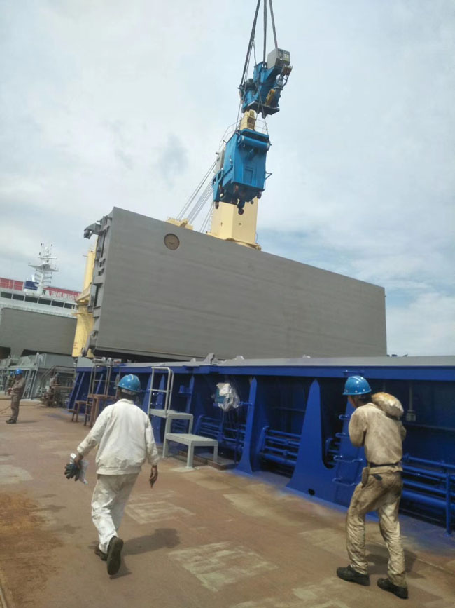 工作人員正在將船艙甲板除銹機(jī)吊到甲板上面